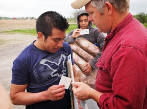 Migrant farm worker Victor Diaz receives a check for back pay from farmer Ray Brands.